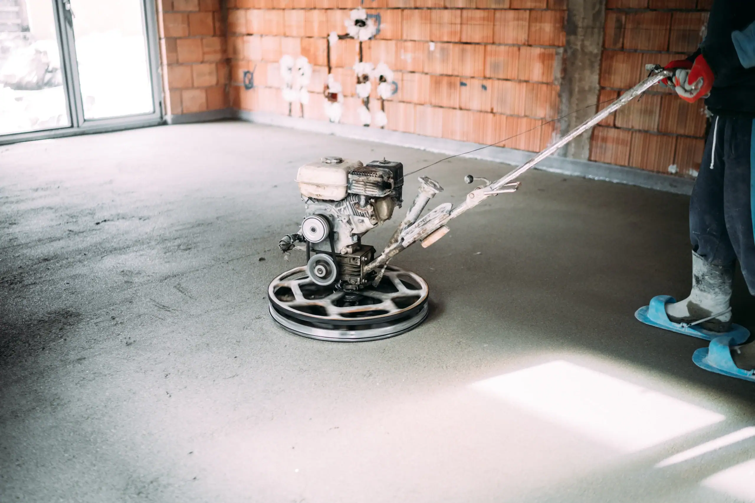 Concrete grinding machine beside a brick wall in a commercial space
