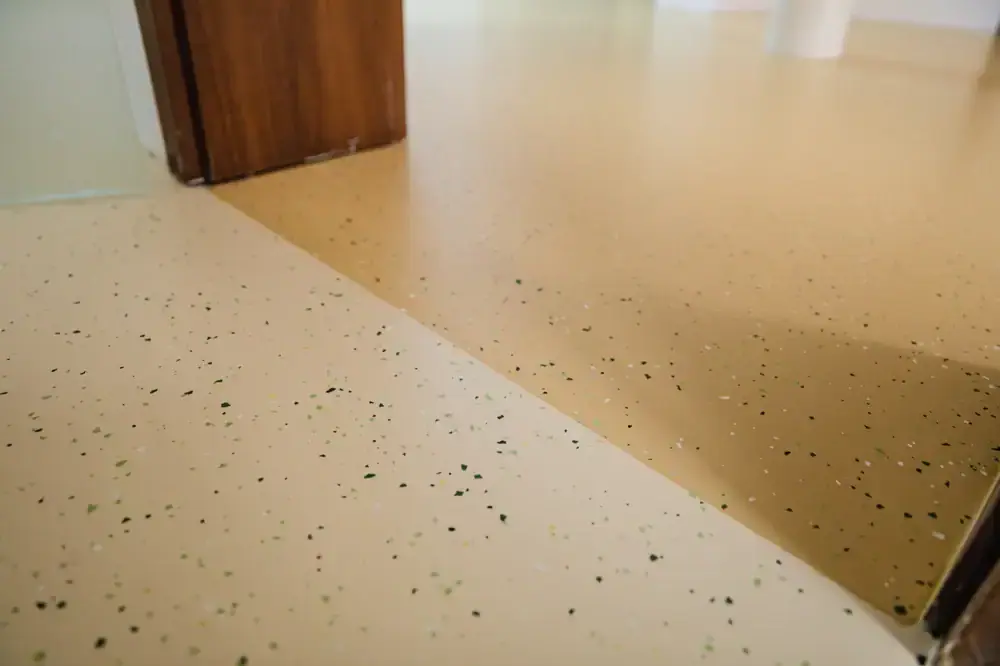 Close-up of beige speckled epoxy chip flooring near a wooden door frame