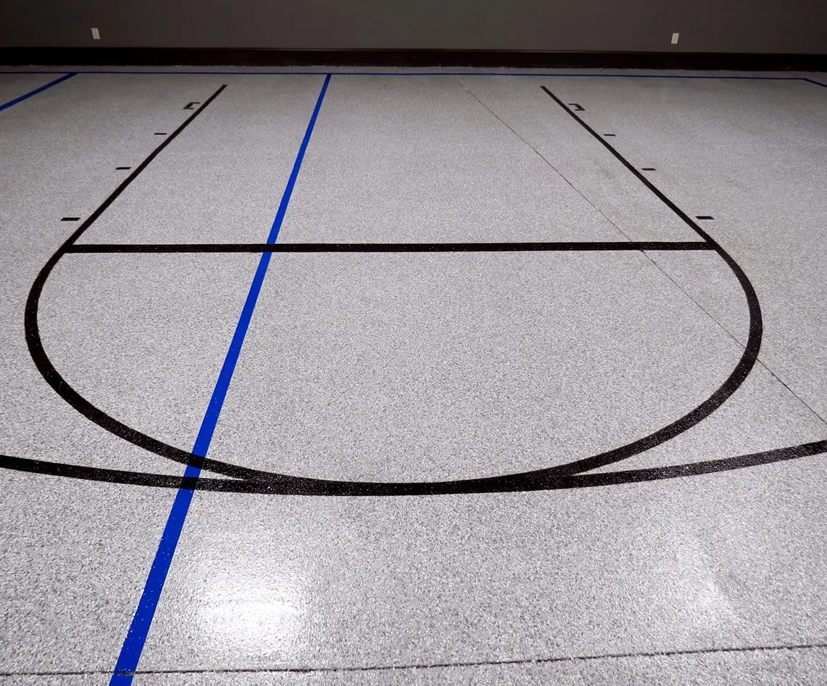 Dark textured epoxy coating applied to a horse stall floor with wood panel walls