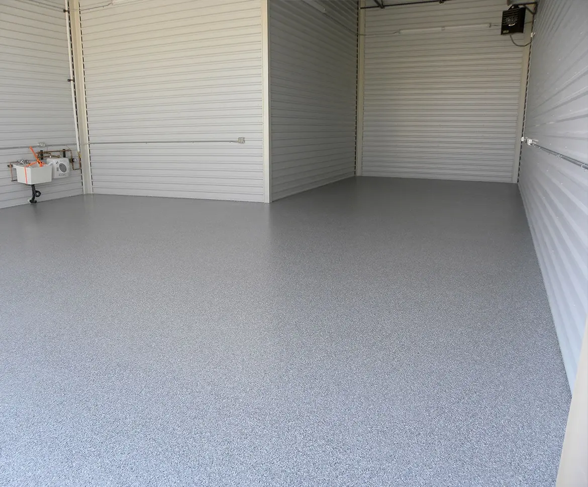 Dark epoxy warehouse floor with vehicle access door open to exterior